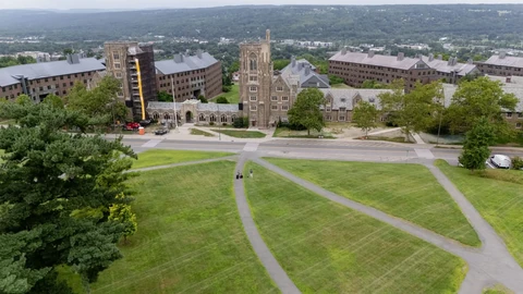 A view of a university campus gate under a grey sky, representing the somber atmosphere surrounding the investigation.