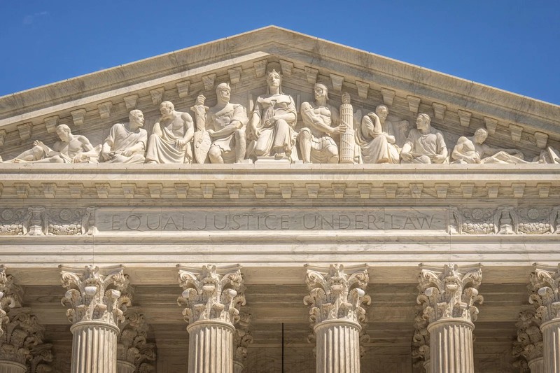 The exterior facade of the Supreme Court building featuring tall marble columns under a clear sky.